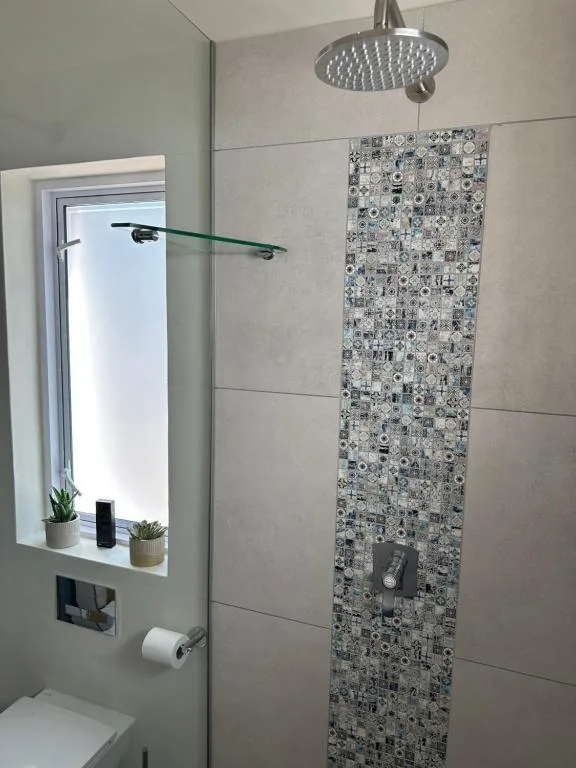 Modern shower with rainfall showerhead and patterned tile accent wall