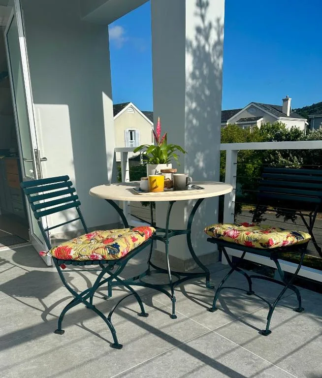 Outdoor patio with round table, chairs, and colorful cushions overlooking neighborhood