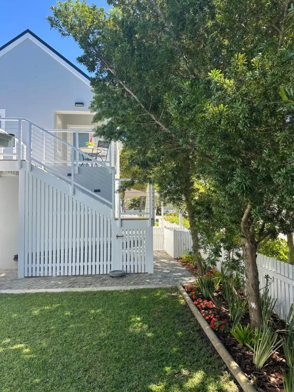 Modern white house with deck, manicured lawn, and mature trees