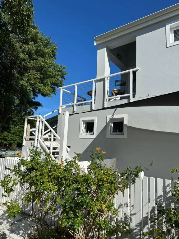 Modern gray and white two-story apartment building with deck and stairs
