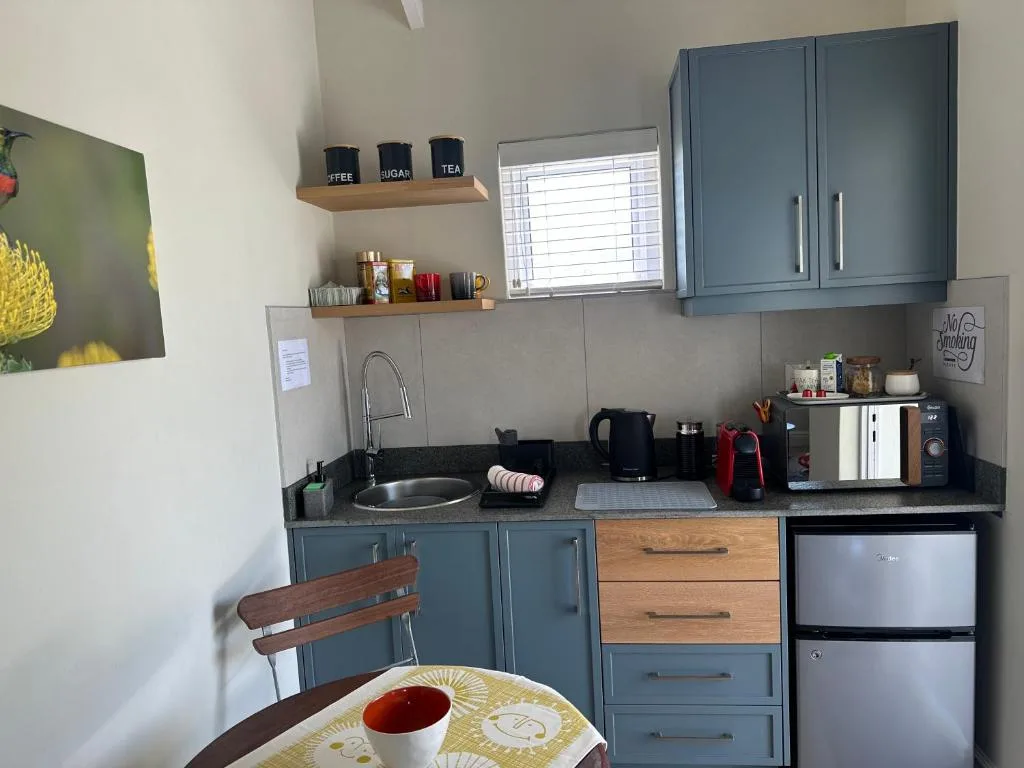 Modern kitchen with blue cabinetry, stainless steel appliances, and open shelving