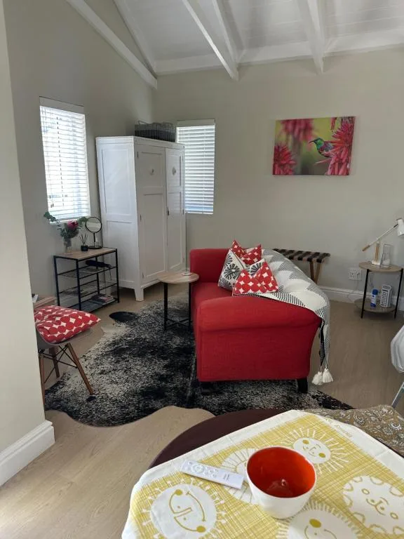 Bright studio lounge with red sofa, white wardrobe, and decorative artwork