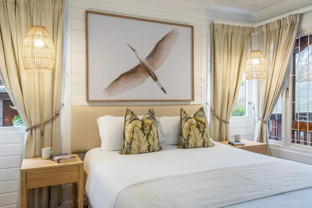 Bright bedroom with white bed, bird artwork, and woven pendant lights