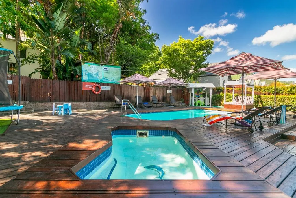 Two swimming pools with loungers and umbrellas in sunny garden setting