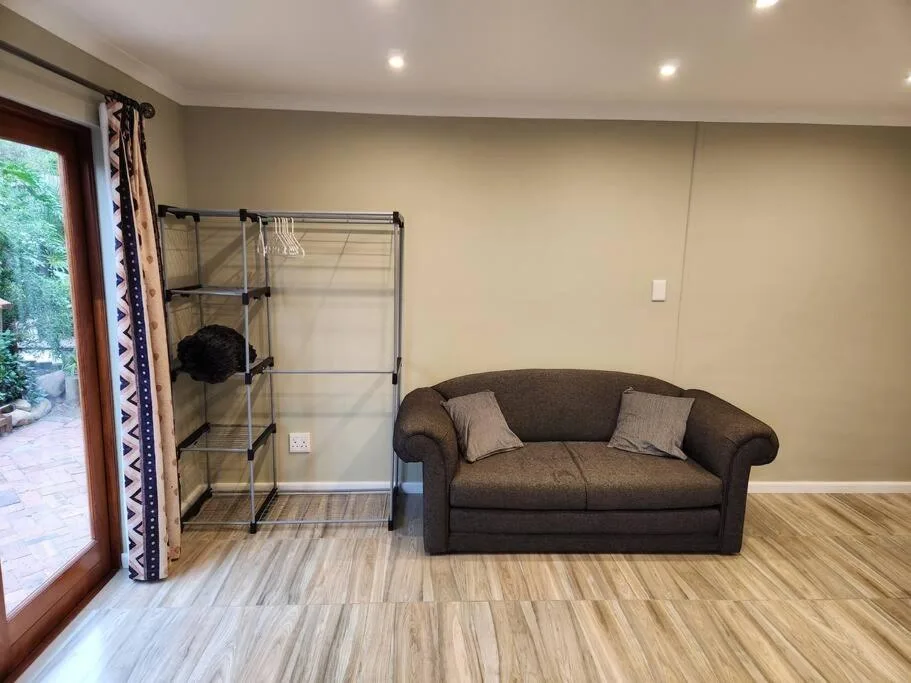 Spacious lounge with brown sofa, wooden floors, and garden access