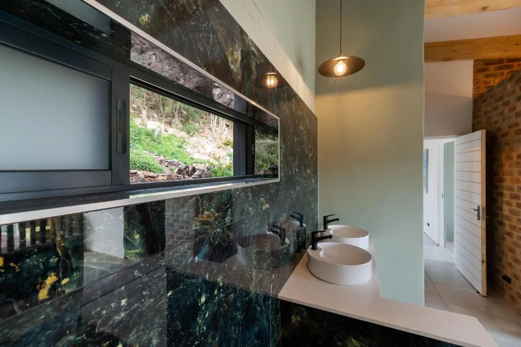 Modern bathroom with dual white vessel sinks and dark marble vanity