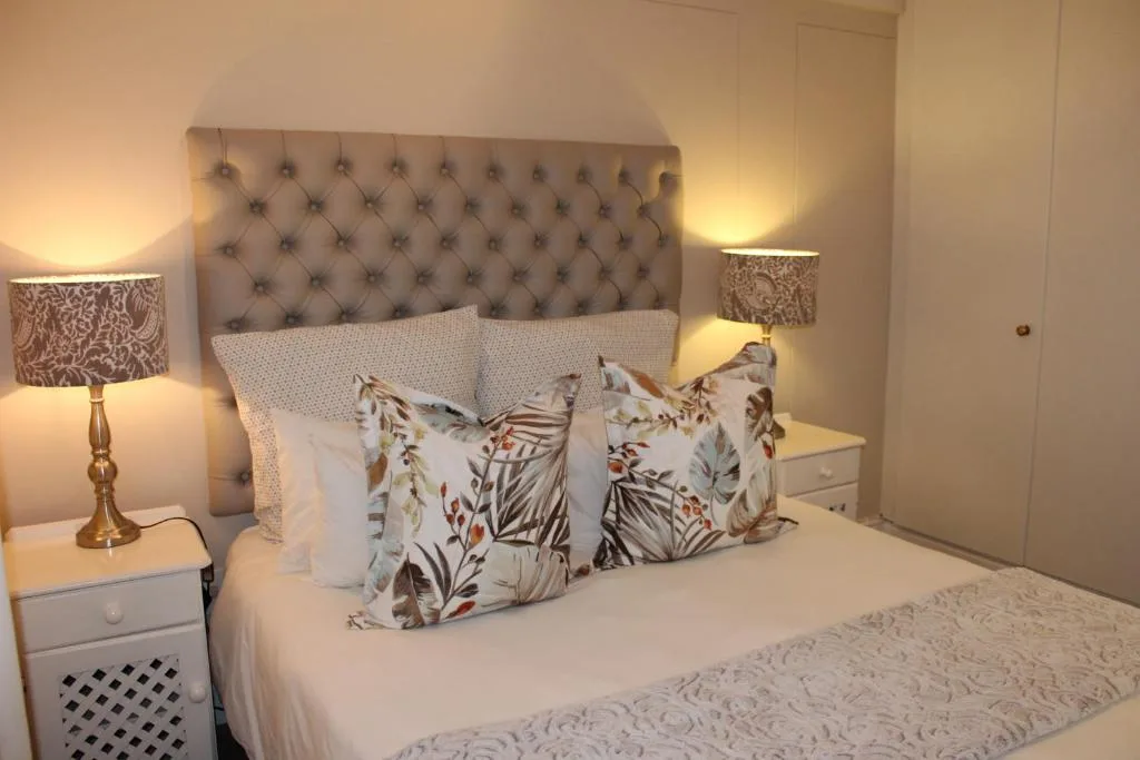 Luxurious bedroom with upholstered headboard, patterned pillows, and warm lighting