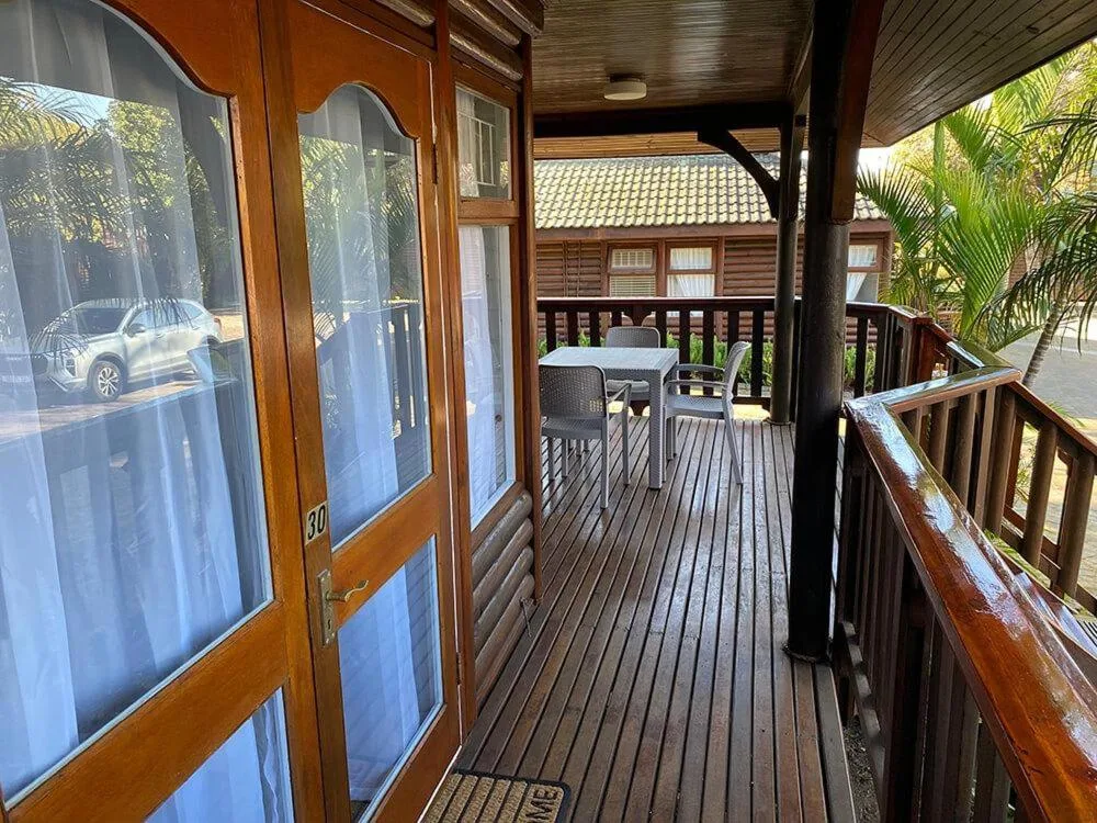 Wooden deck with outdoor seating, railing, and tropical vegetation view