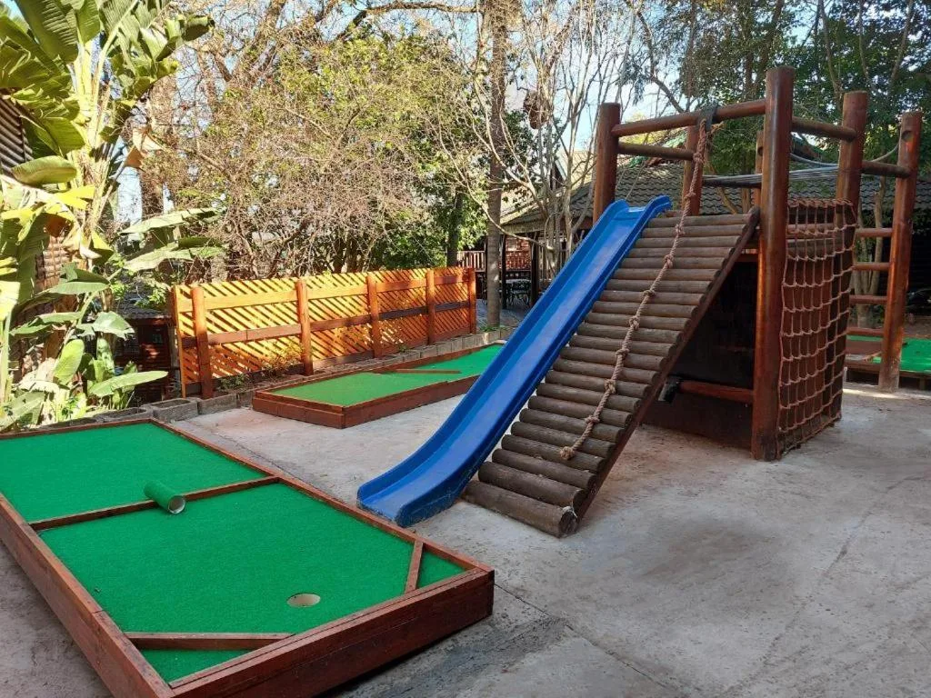 Mini golf course and wooden play structure with blue slide in garden
