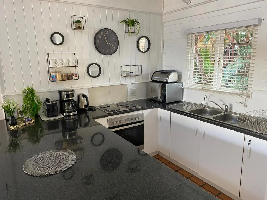Modern kitchen with black countertops, white cabinetry, stove, and sink area