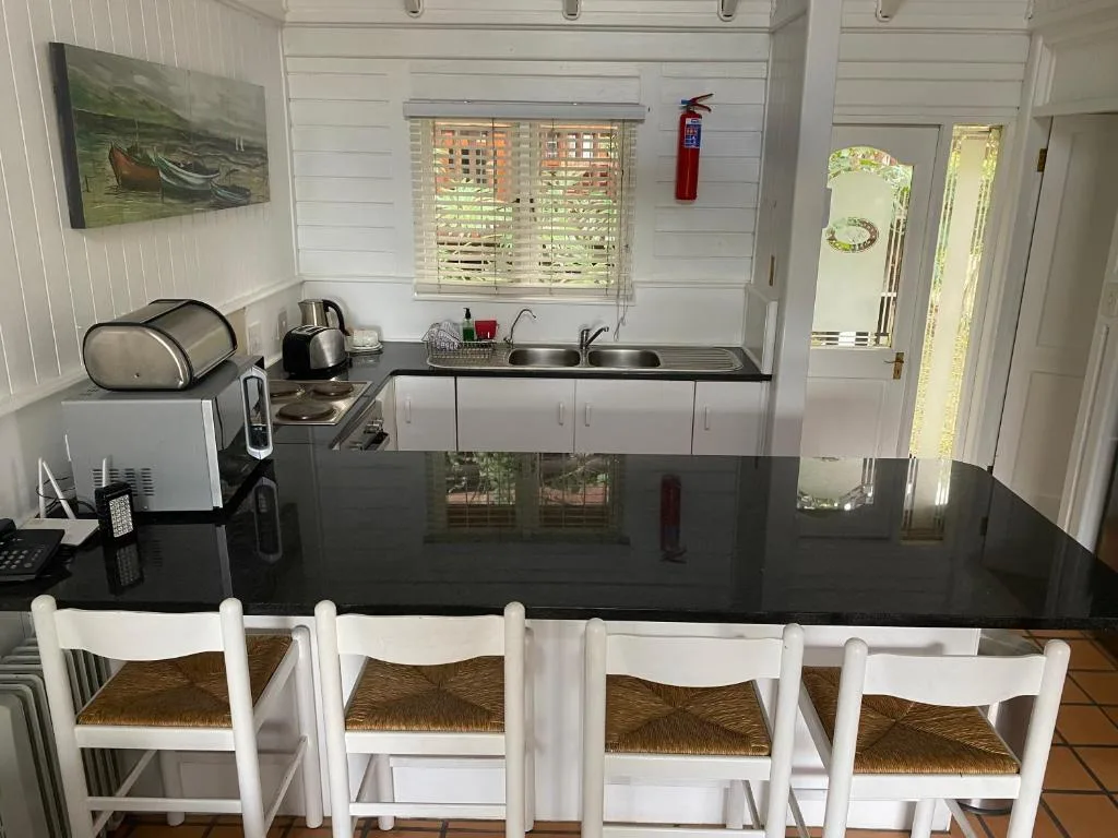 Modern kitchen with black countertop, white cabinetry, and dining chairs