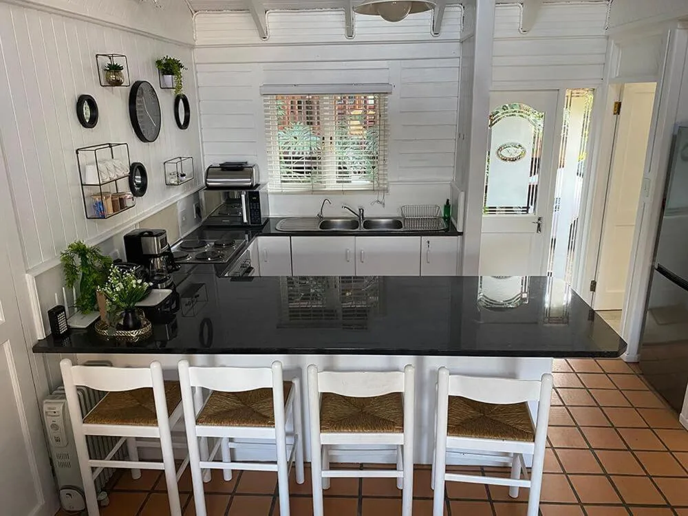 Modern kitchen with black countertop, white cabinetry, and bar seating