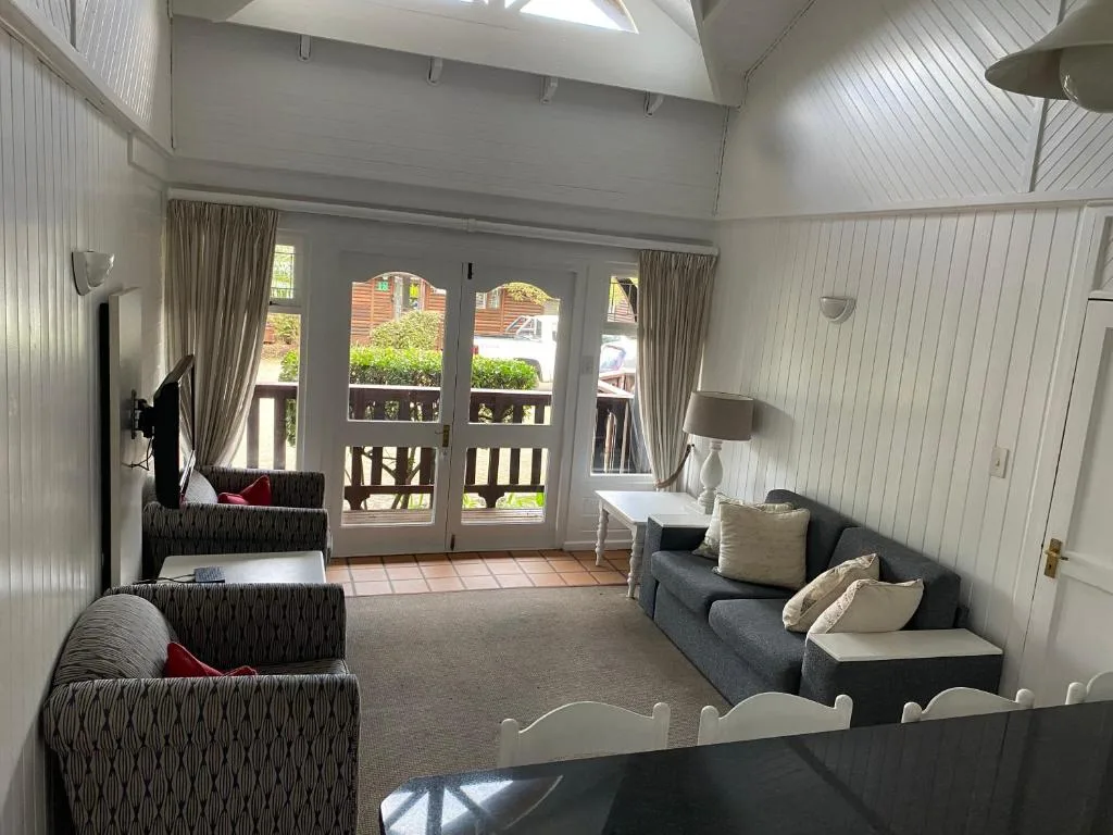 Bright lounge with multiple sofas, high ceiling, and French doors opening to garden