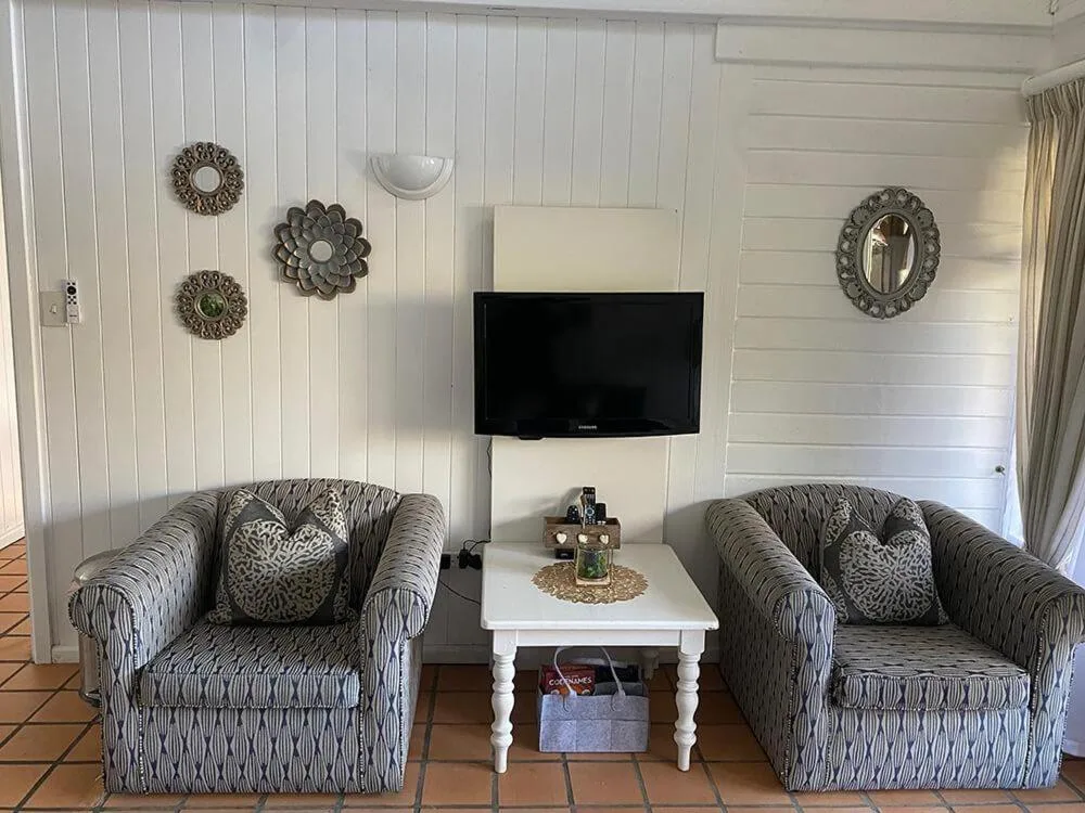 Spacious living room with two patterned armchairs and wall-mounted television
