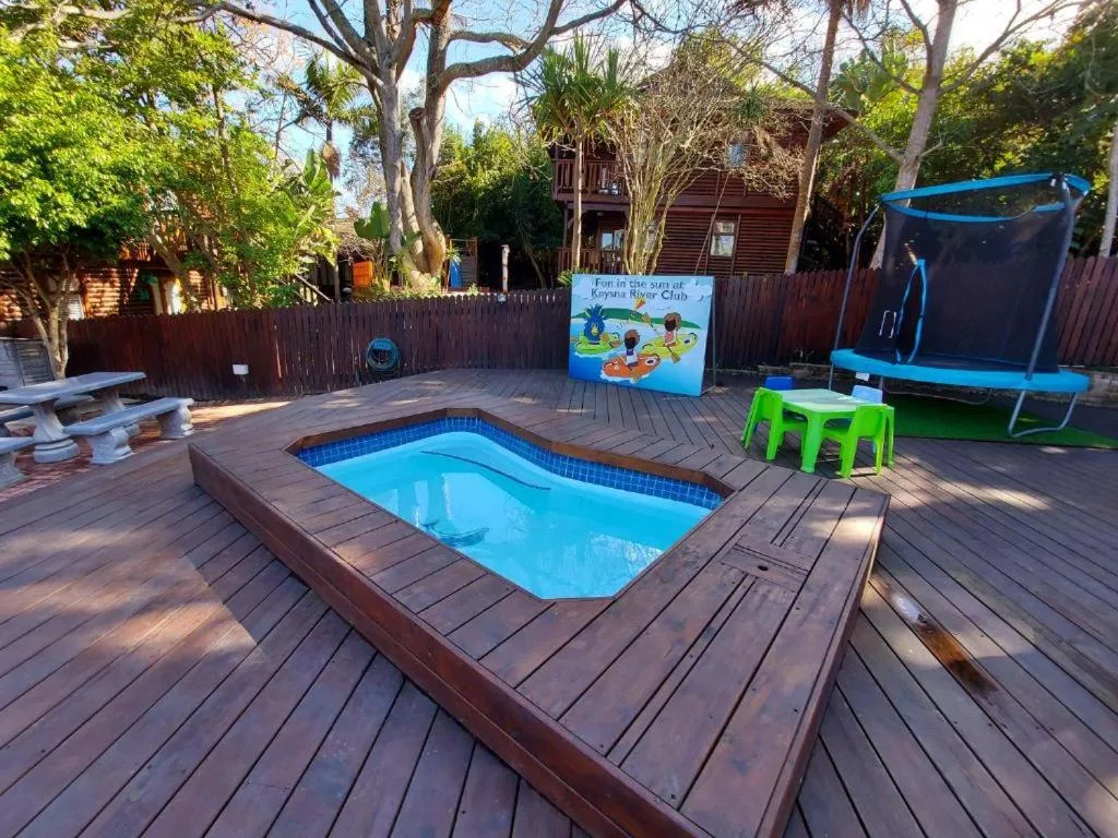 Swimming pool set in wooden deck with recreational amenities and trees