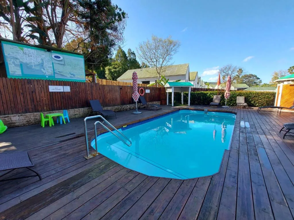 Bright blue swimming pool on wooden deck with loungers and landscaped gardens