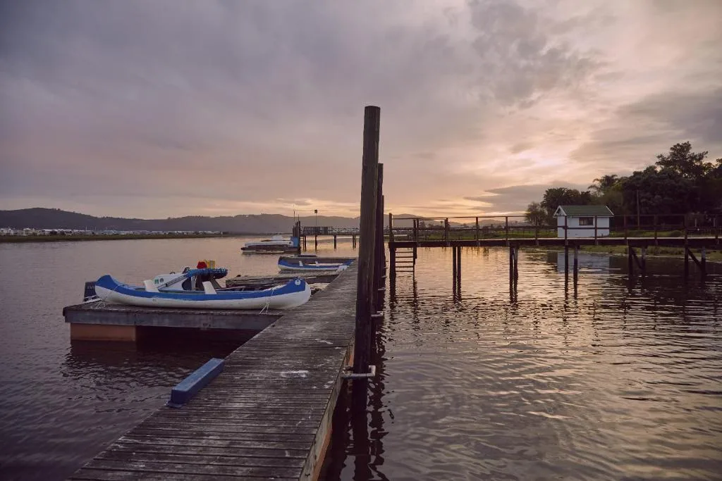 Scenic sunset over Knysna lagoon with moored boats and wooden jetty