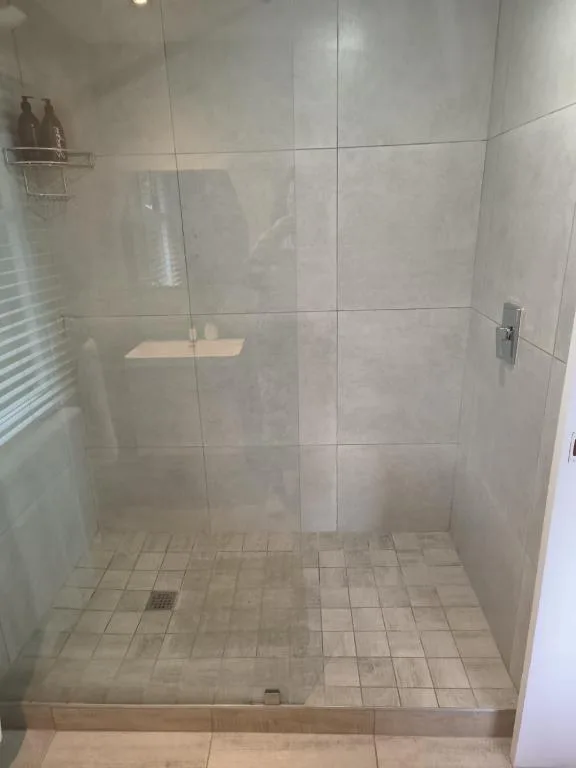 Modern walk-in shower enclosure with large glass door and neutral tile