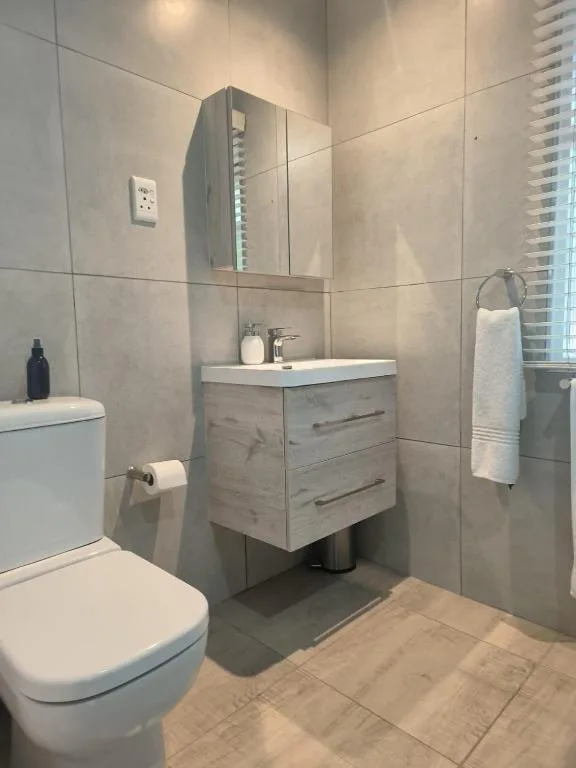 Modern bathroom with vanity, mirrored cabinet, and white toilet fixtures