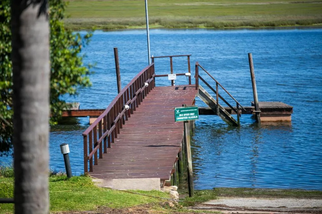 Wooden jetty with railings extending into calm blue water