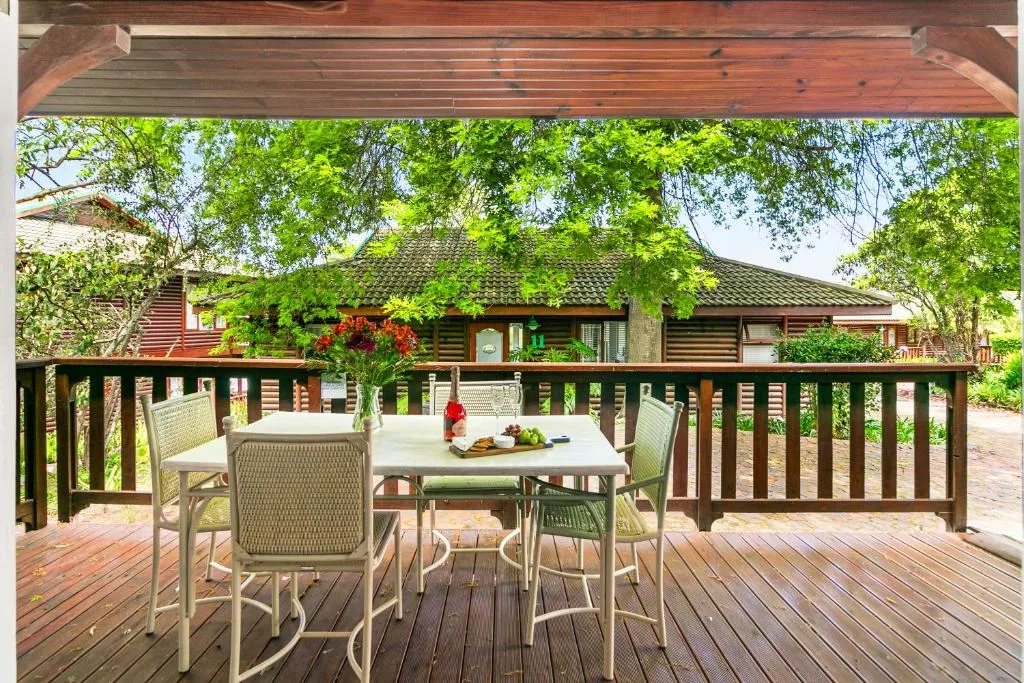 Wooden deck with dining table and chairs overlooking lush garden views