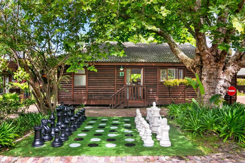 Wooden cottage with garden featuring giant chess pieces and mature trees