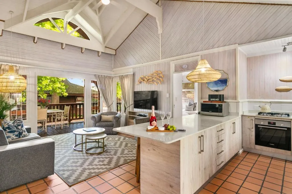 Open-plan lounge with sofa, TV, and kitchen island visible beyond