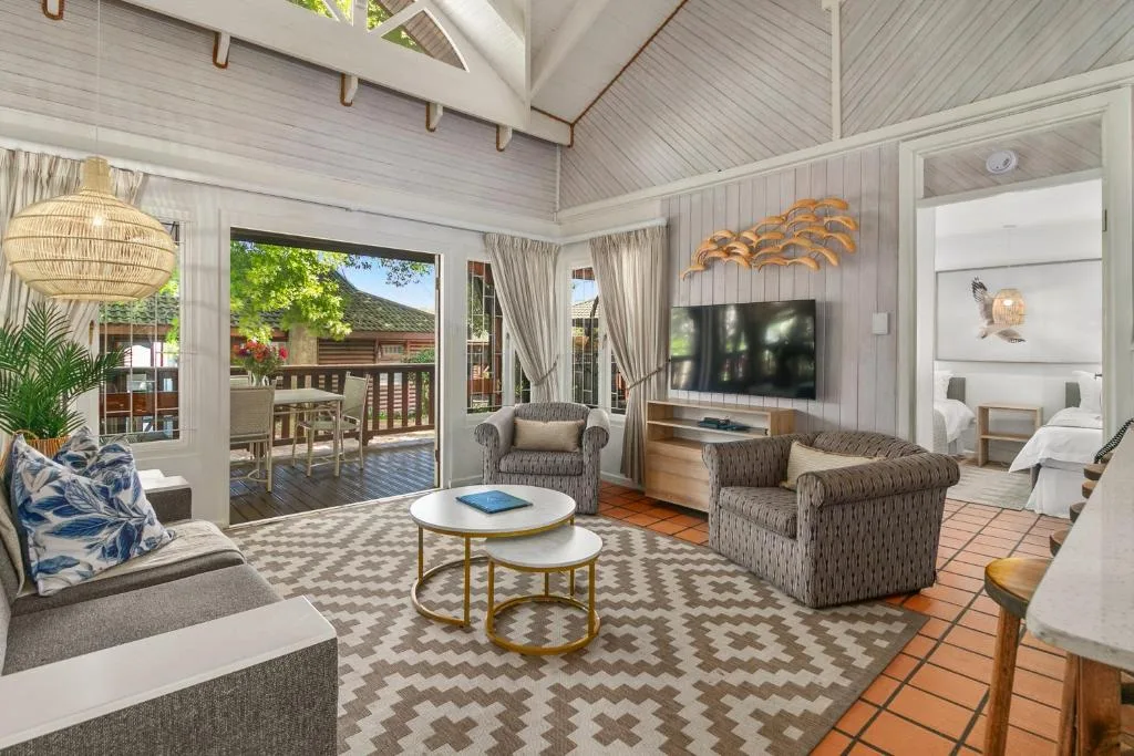 Bright open-plan lounge with comfortable seating, TV, and outdoor deck access