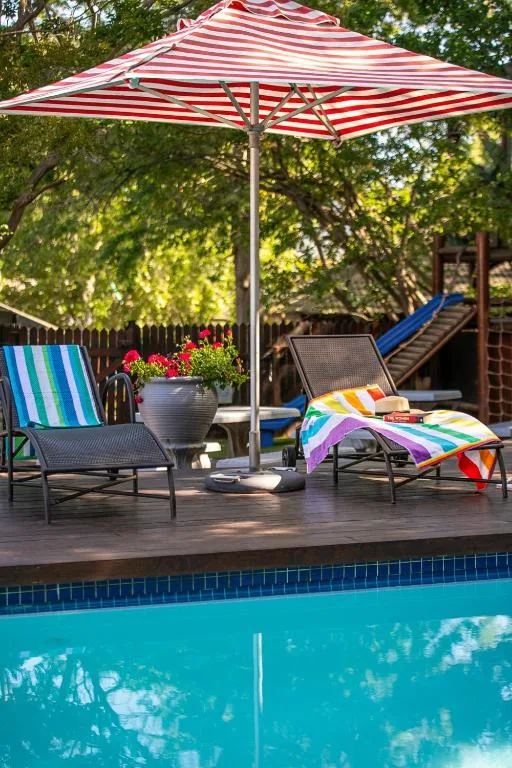 Swimming pool with loungers, umbrella, and colorful towels nearby