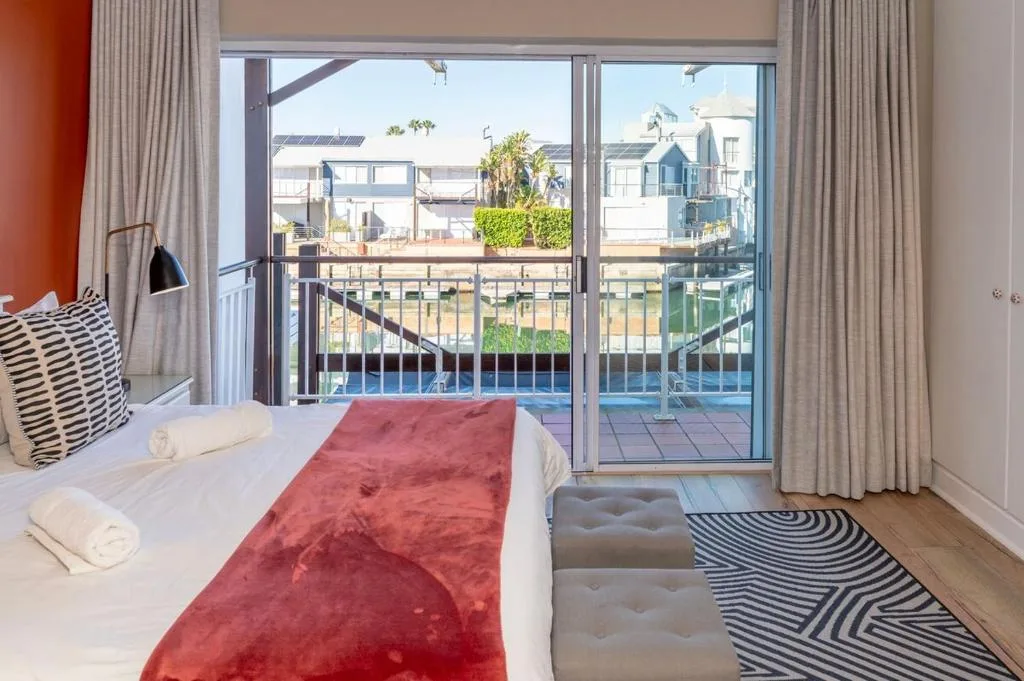 Bright bedroom with queen bed overlooking lagoon and deck access to water