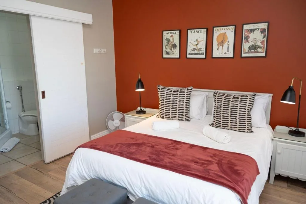 Bright bedroom with queen bed, rust-colored walls, and en-suite bathroom visible