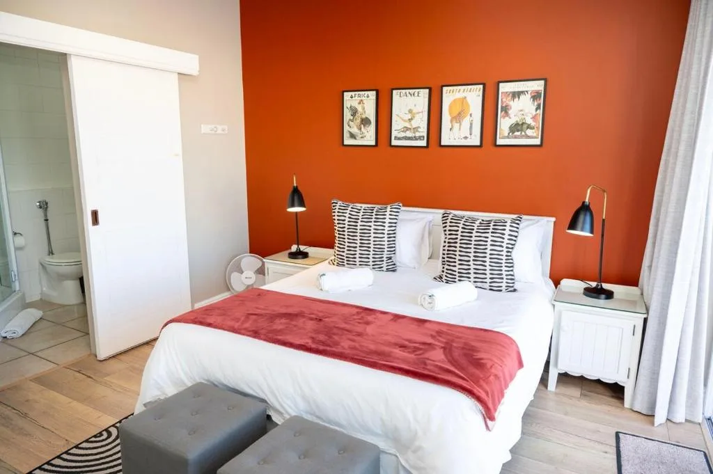 Bright bedroom with vibrant orange accent wall and white bedding