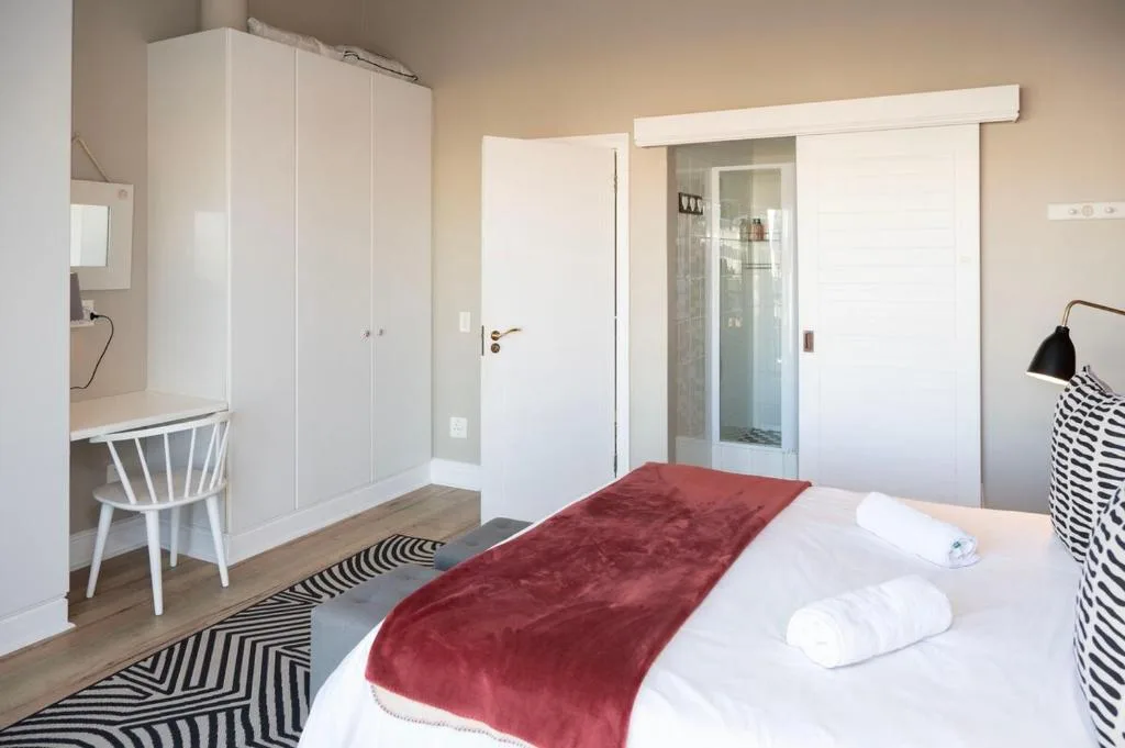Bright bedroom with bed, wardrobe, desk, and ensuite bathroom entrance