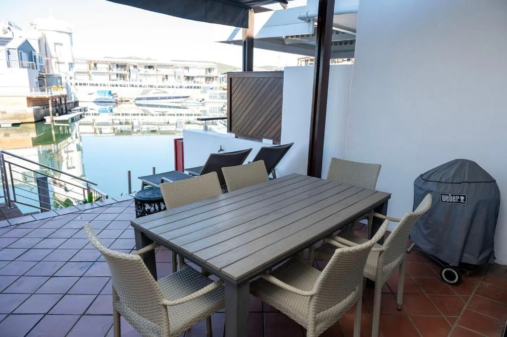 Waterfront deck with dining table, chairs, and lagoon views