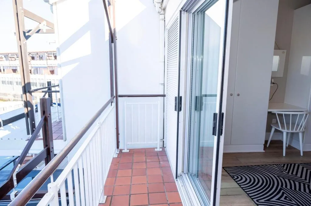 Narrow balcony with terracotta tiles and water views beyond railing