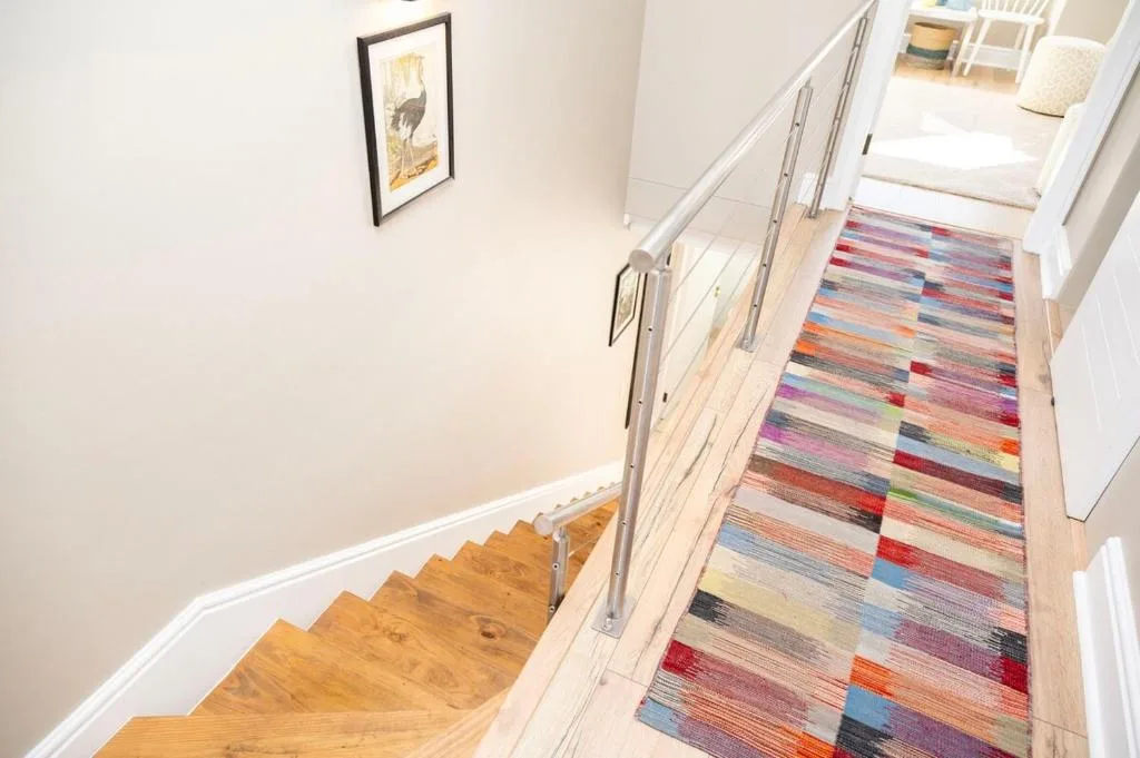 Wooden staircase with colorful striped runner and metal railing