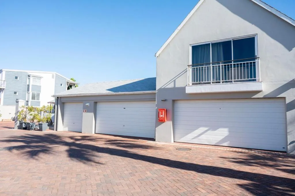 Modern white villa with double garage and balcony overlooking brick driveway