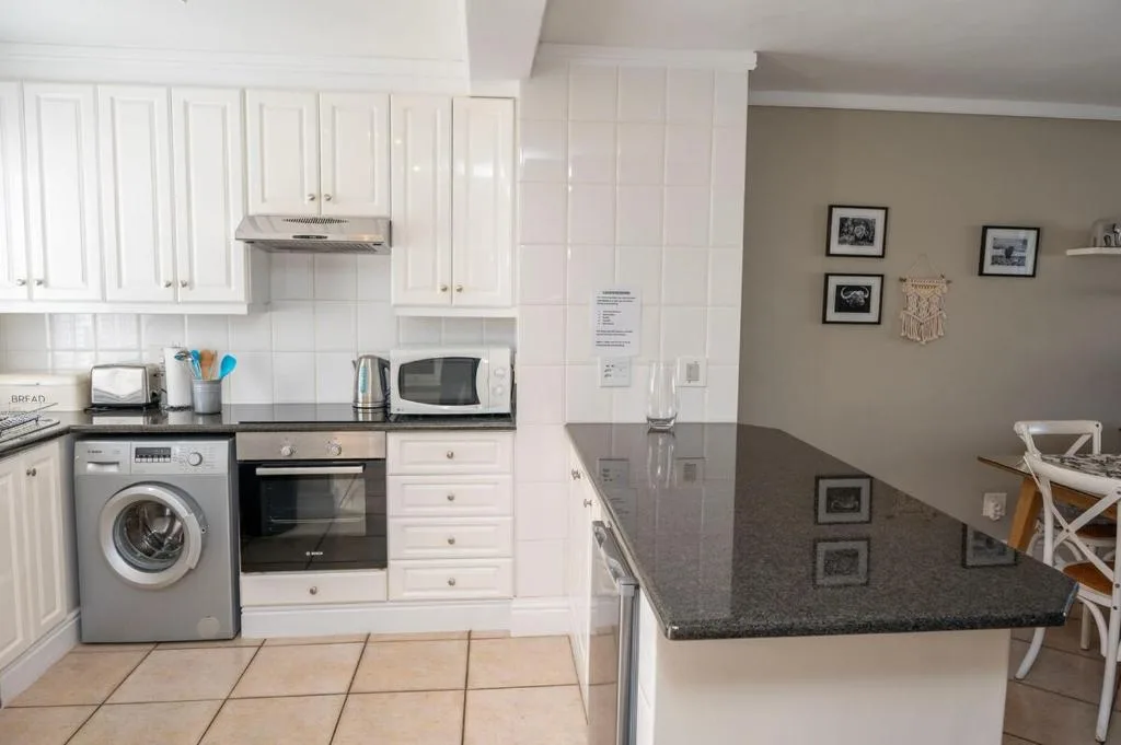 Modern white kitchen with black countertops, stainless steel appliances and island
