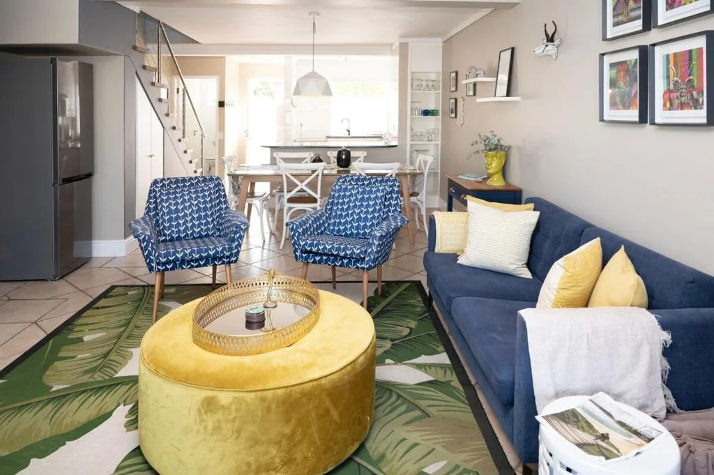 Open-plan lounge with navy sofa, blue patterned armchairs, and yellow poufs