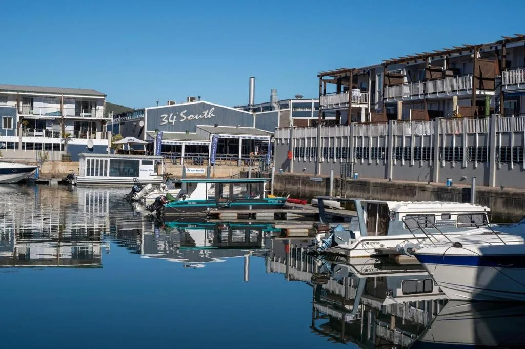 Waterfront buildings and moored boats reflecting in calm lagoon water