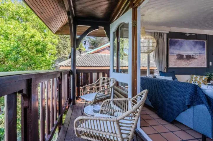Covered deck with wicker chairs overlooking lush green surroundings and lagoon views