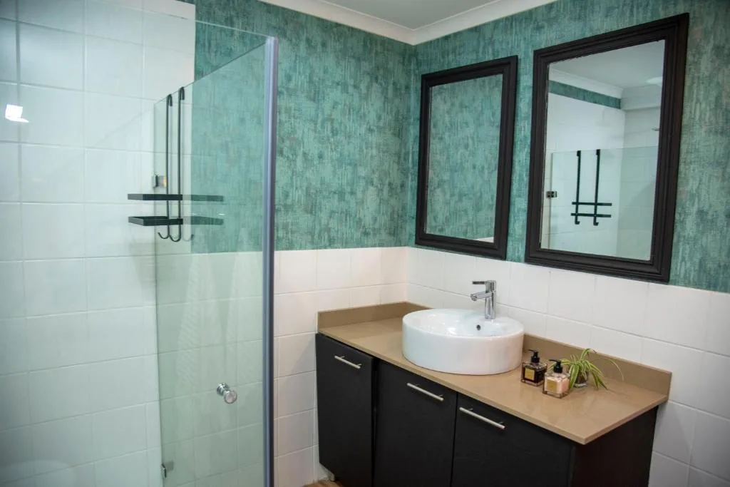 Modern bathroom with dual vanity, round sink, and glass shower enclosure