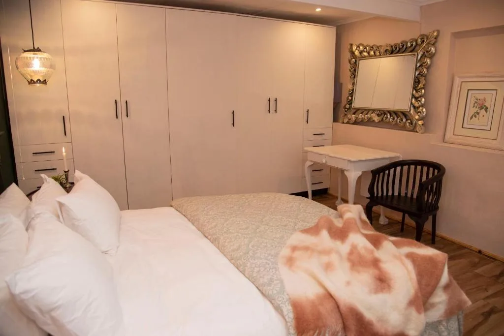 Spacious bedroom with queen bed, built-in wardrobes, and elegant gold-framed mirror