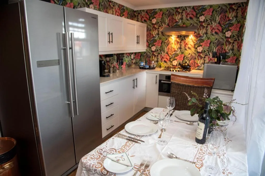 Modern white kitchen with stainless steel appliances and floral wallpaper