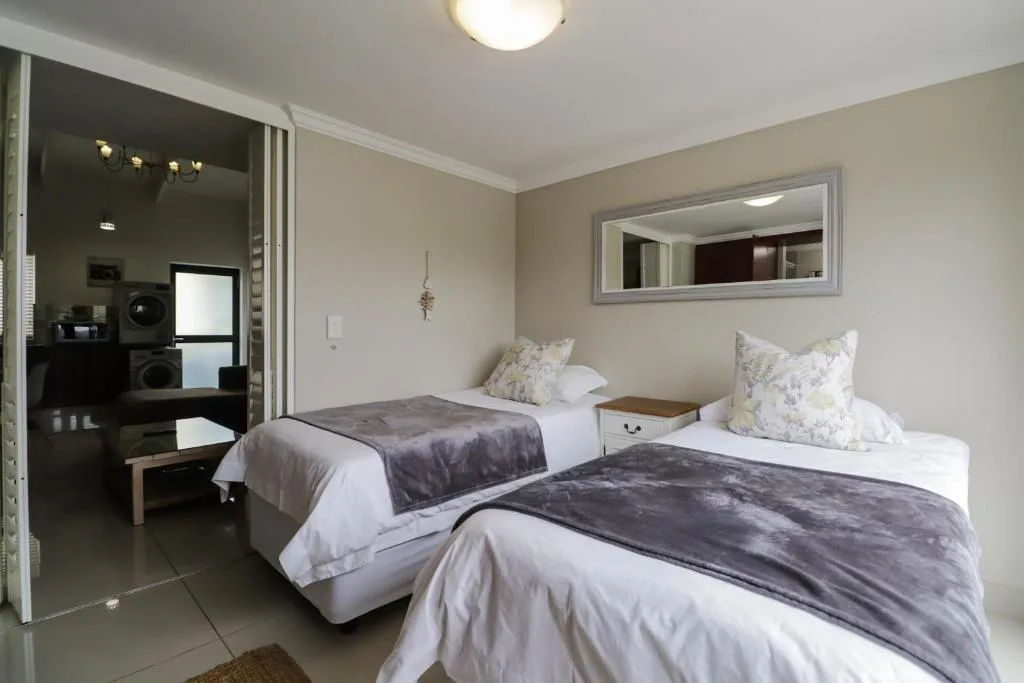 Twin bedroom with white linens, gray throws, and modern decor