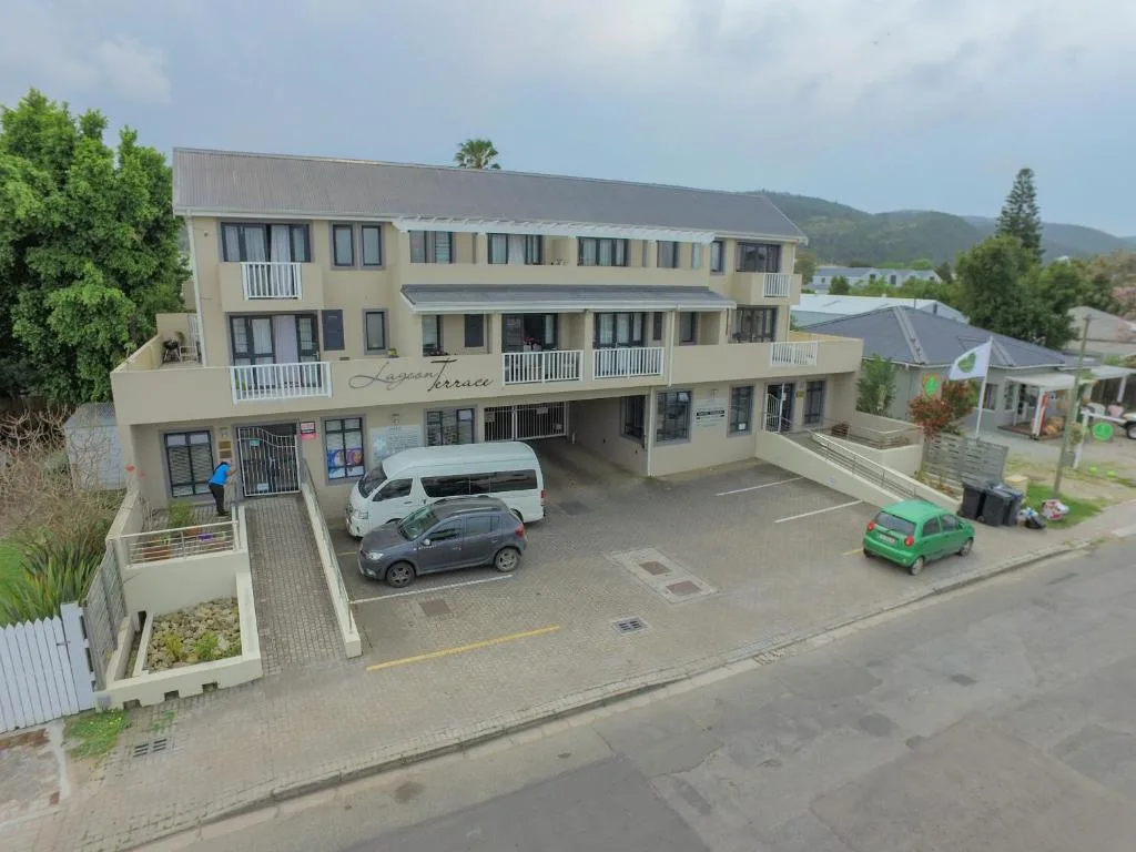 Multi-story cream building with parking area and mountain views behind