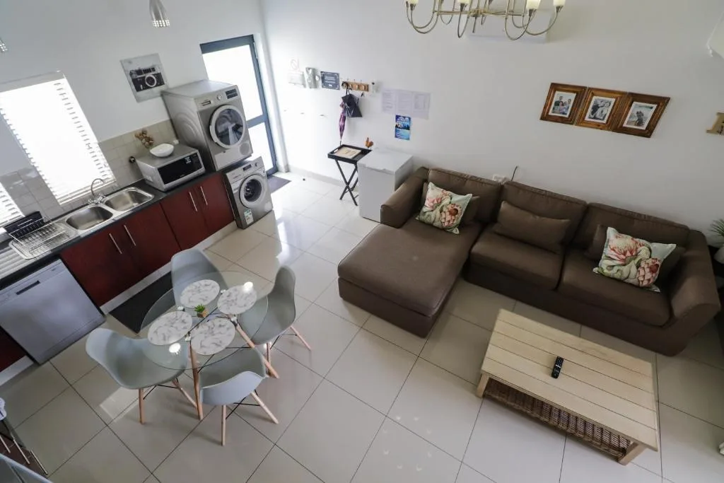 Open-plan lounge with brown sofa, dining area, and kitchen visible