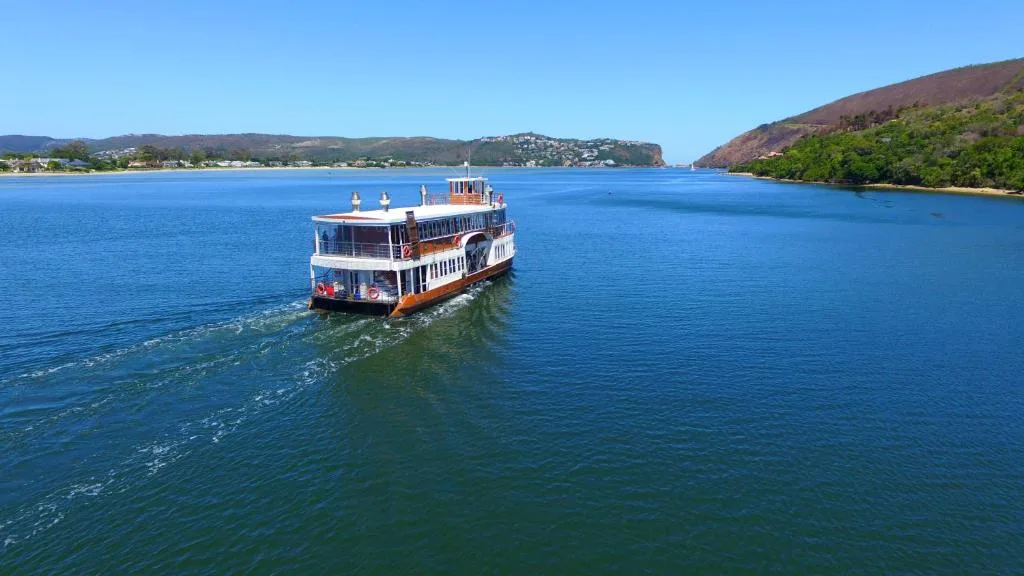 Scenic lagoon view with tour boat and green hillsides, Knysna