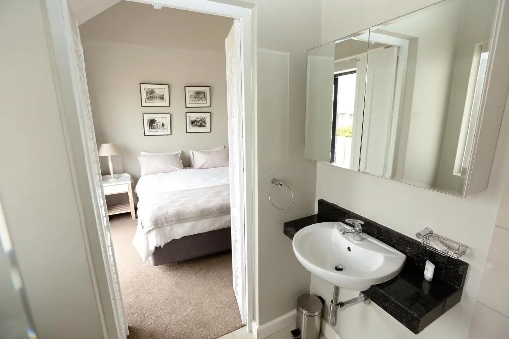 Modern bathroom with white sink, large mirror, and black countertop