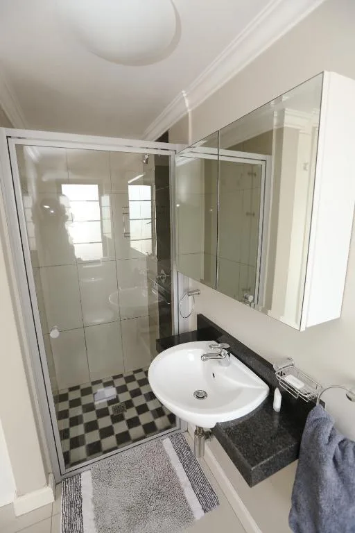 Modern bathroom with shower enclosure, round sink, and checkered floor tiles